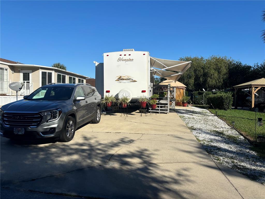 A gray SUV is parked on a concrete driveway in front of a white travel trailer — 3097 NE 102ND AVENUE ROAD, SILVER SPRINGS, FL