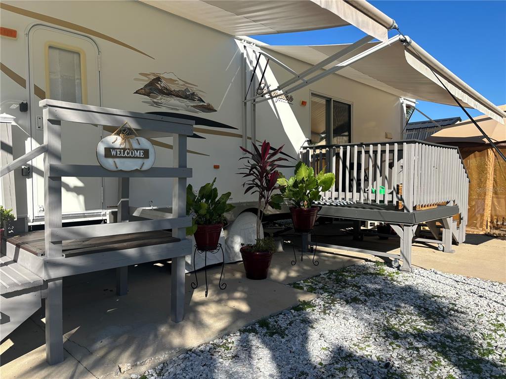 A recreational vehicle features a wooden deck, a welcome sign, and potted plants outside — 3097 NE 102ND AVENUE ROAD, SILVER SPRINGS, FL