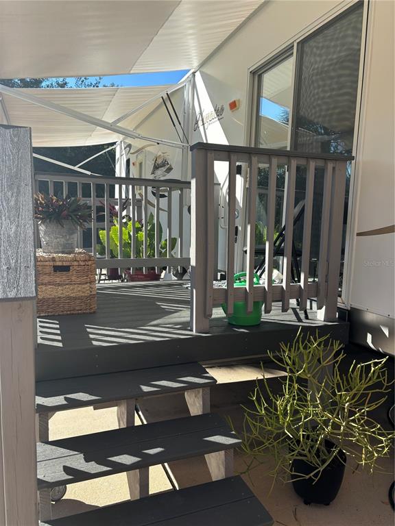 A grey wooden deck with stairs and railings sits beside a parked recreational vehicle — 3097 NE 102ND AVENUE ROAD, SILVER SPRINGS, FL