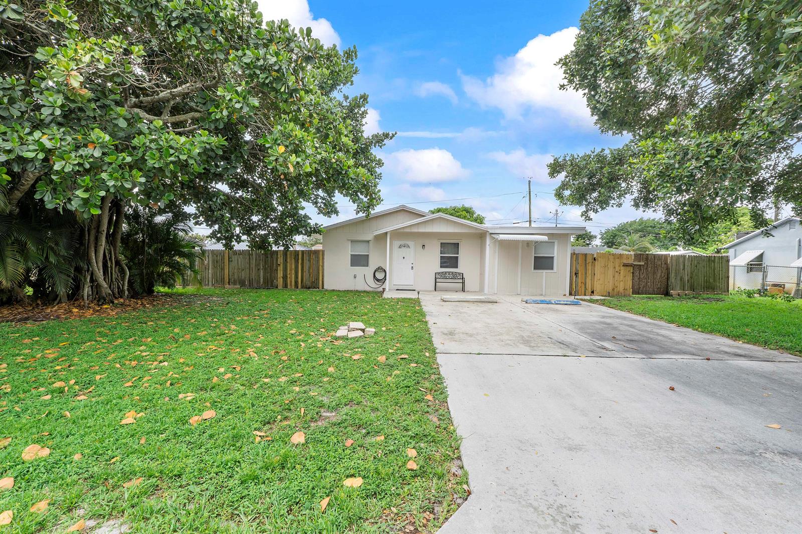 A single-story house with a concrete driveway and a large tree in the front yard — 3344 Plaza Place, Lake Worth FL 33462, LAKE WORTH, FL