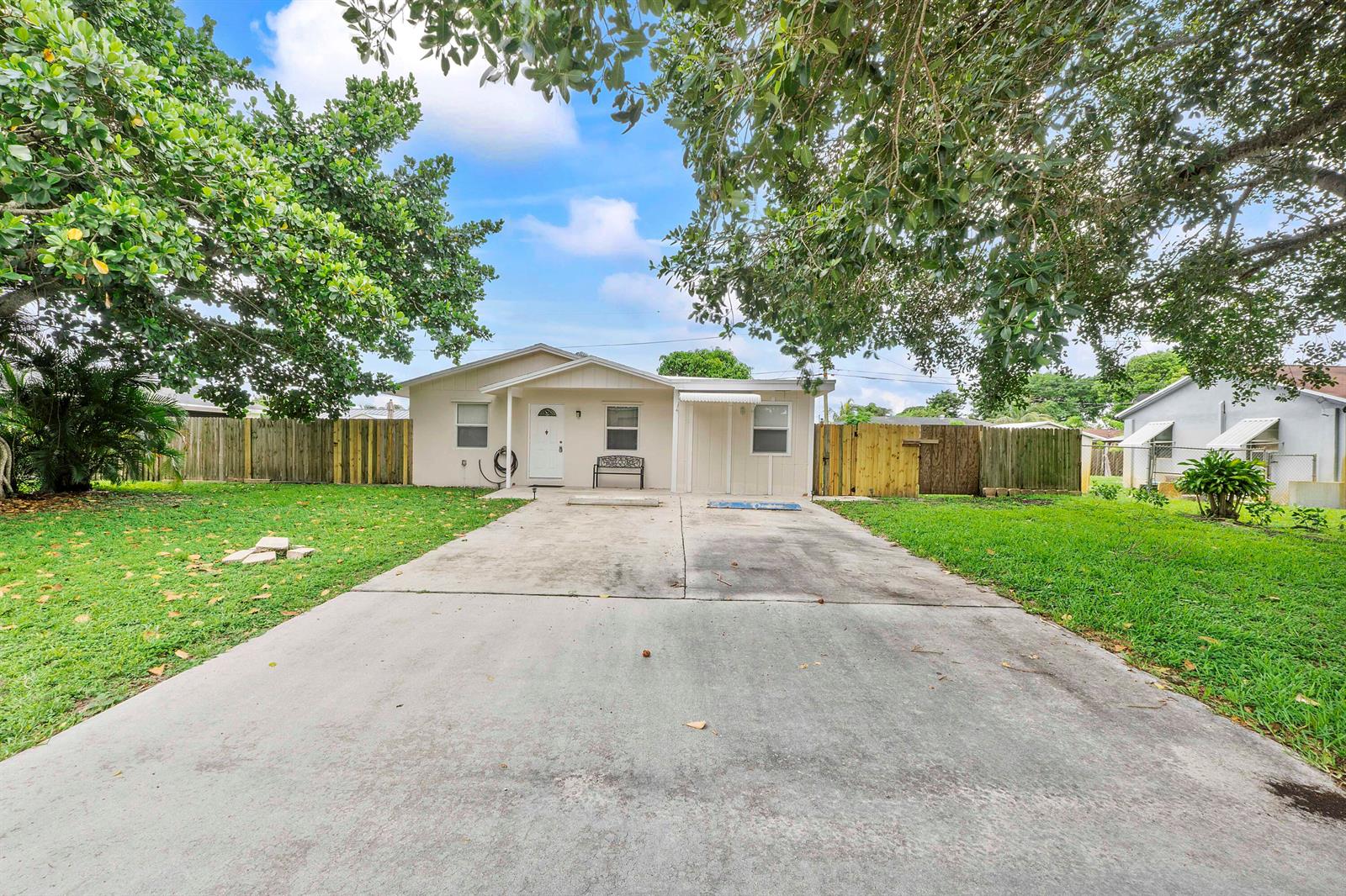 A single-story house with a concrete driveway, a white front door, and a wooden fence — 3344 Plaza Place, Lake Worth FL 33462, LAKE WORTH, FL