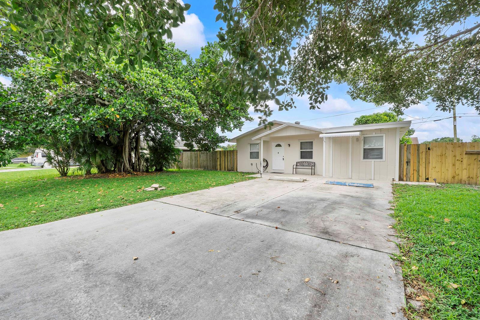 A single-story house with a concrete driveway, a front door, and a large shade tree — 3344 Plaza Place, Lake Worth FL 33462, LAKE WORTH, FL