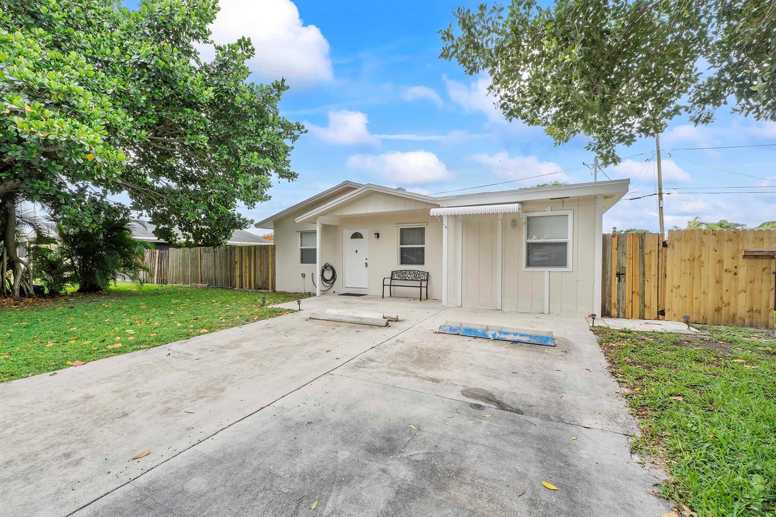 A single-story house with a concrete driveway, a small front porch, and a wooden fence — 3344 Plaza Place, Lake Worth FL 33462, LAKE WORTH, FL