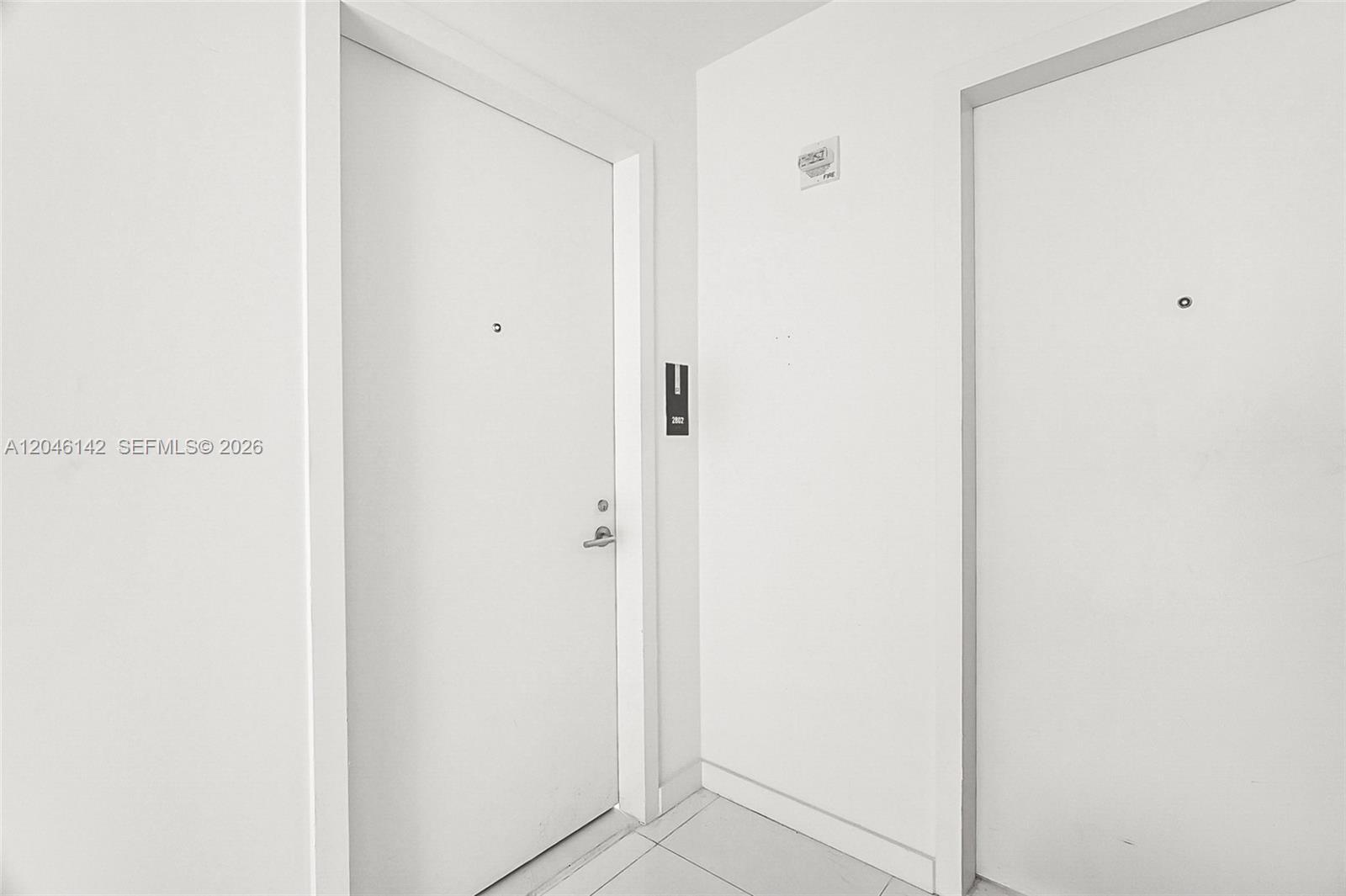 Two white apartment doors are positioned at a corner in a hallway with tiled floors — 851 NE 1st Ave # 2802, Miami FL 33132, MIAMI, FL