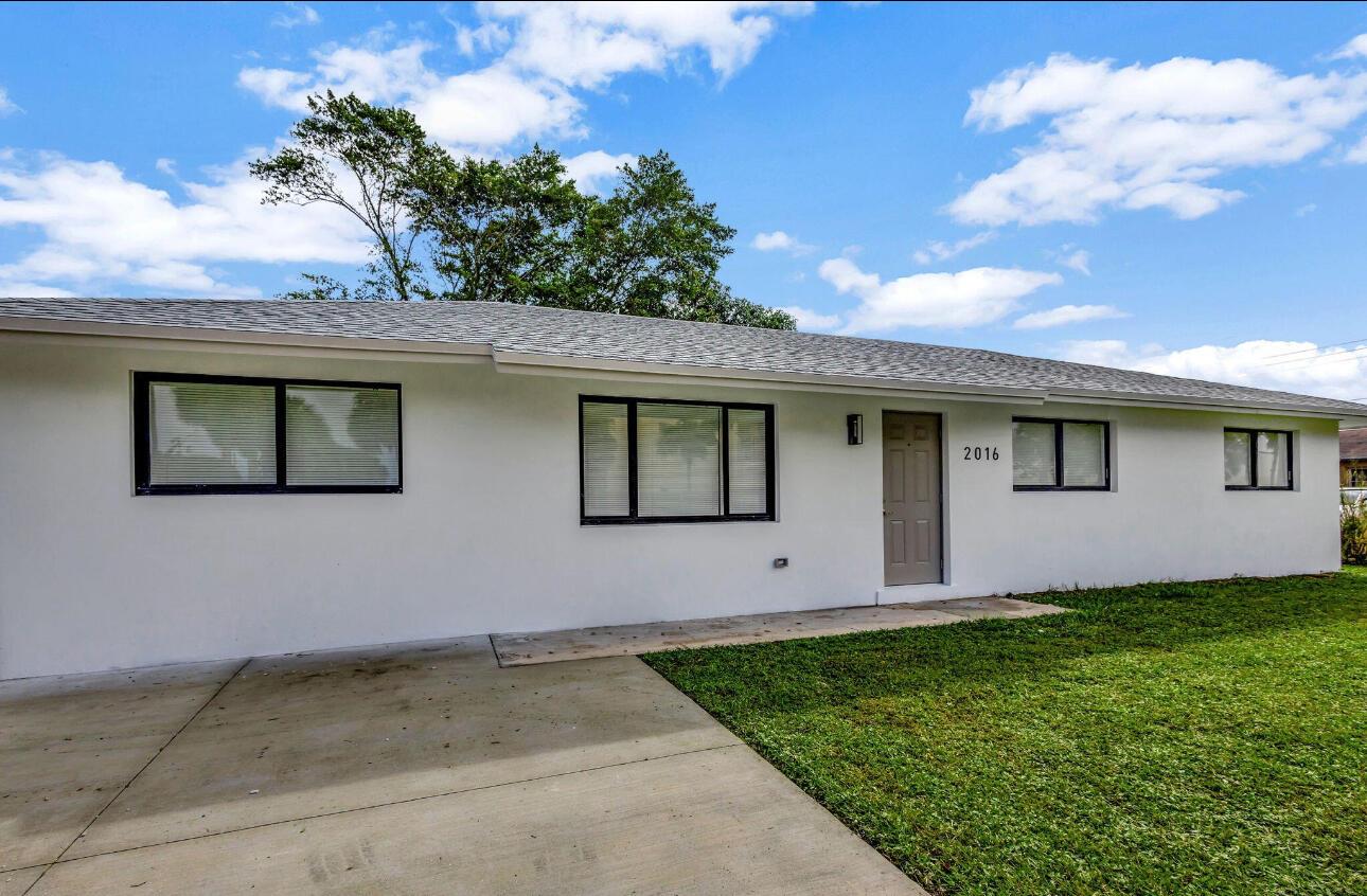 A single-story house with a white exterior, gray roof, and a concrete driveway — 2016 Avenue S, Riviera Beach FL 33404, RIVIERA BEACH, FL