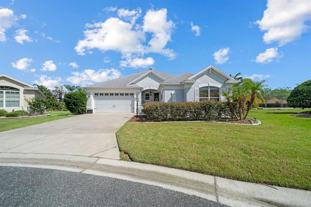 A single-story suburban house with a two-car garage, gray siding, and a manicured front lawn — 1606 SNELLING AVENUE, THE VILLAGES, FL