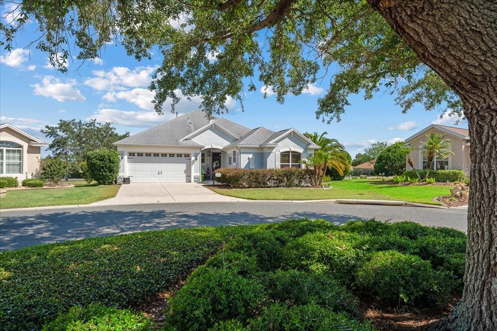A single-story house with a white garage and light-colored siding sits behind a manicured lawn — 1606 SNELLING AVENUE, THE VILLAGES, FL