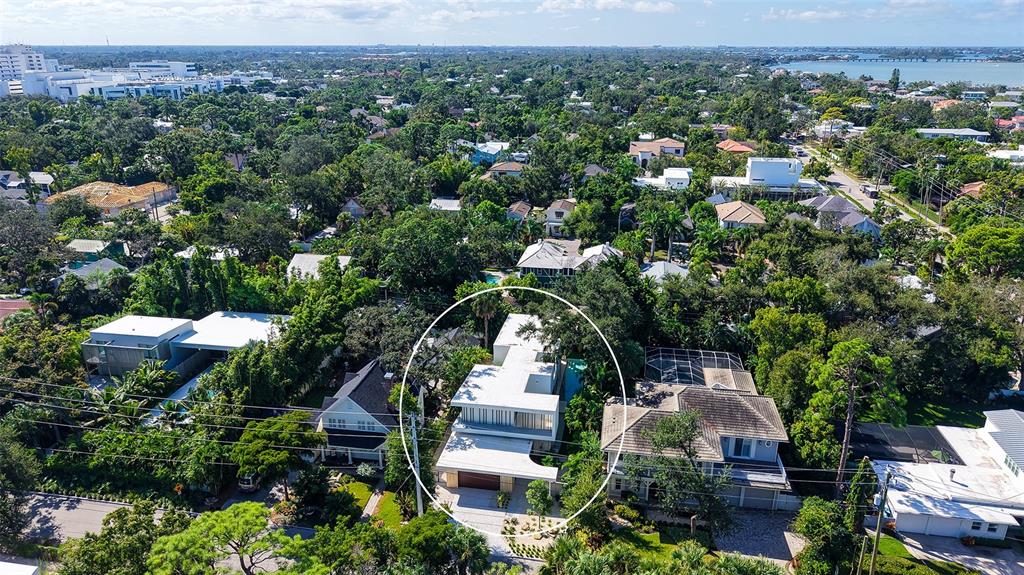 An aerial view shows a modern, multi-level white house surrounded by lush green trees — 1642 BAHIA VISTA STREET, SARASOTA, FL