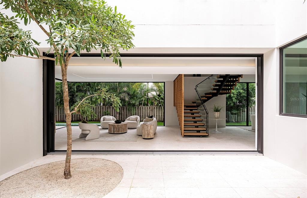 A modern house with a flat roof and stone facade stands next to a traditional home — 1642 BAHIA VISTA STREET, SARASOTA, FL