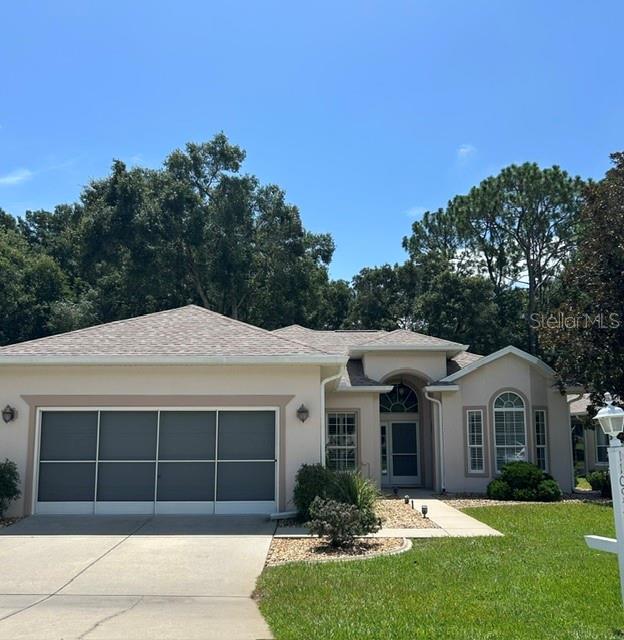 A single-story house with a beige stucco exterior, a multi-car garage, and a landscaped yard — 11093 SW 69TH CIRCLE, OCALA, FL