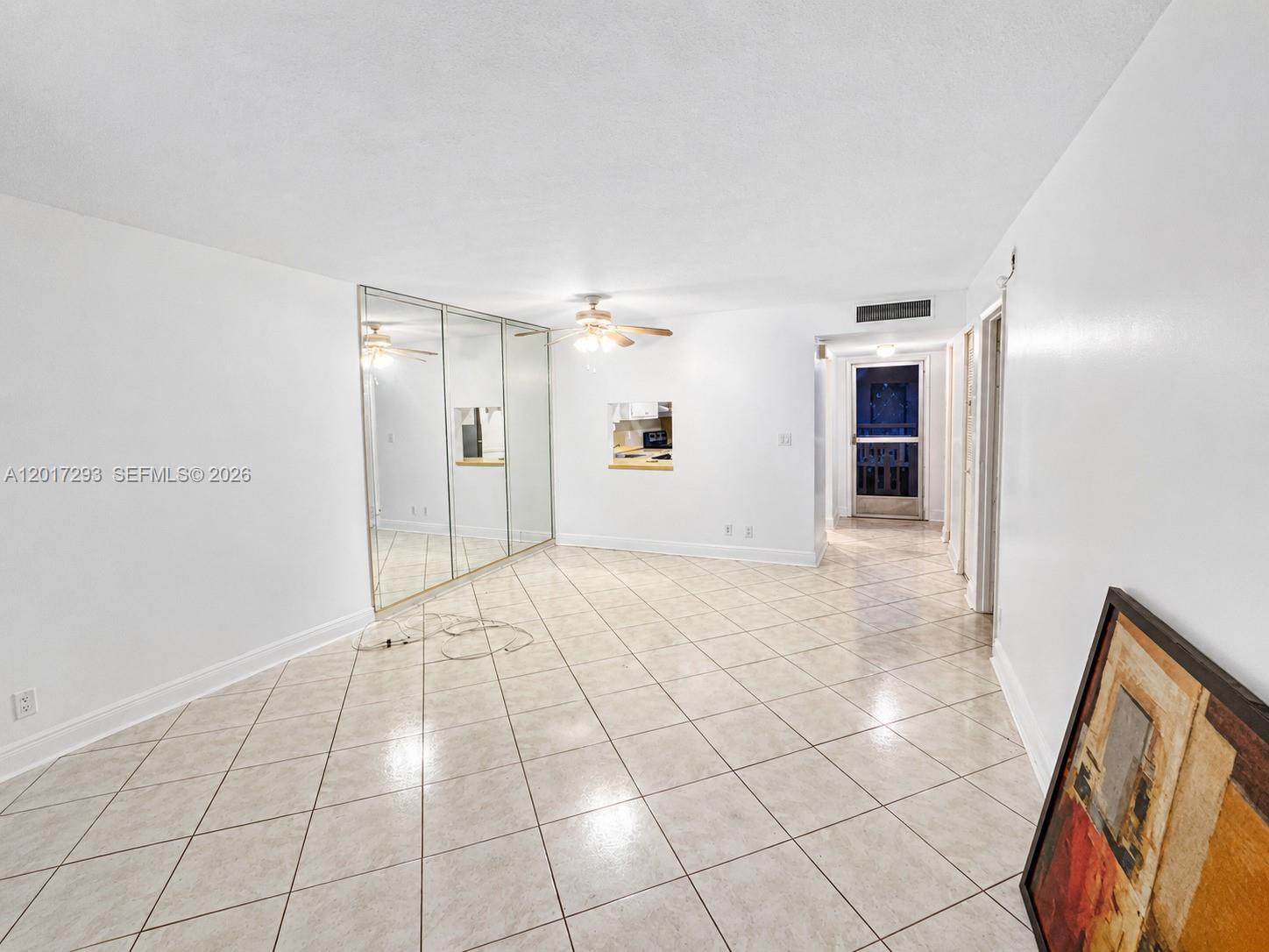 A living room features white walls, tiled floors, mirrored closet doors, and a ceiling fan — 410 SE 2nd St # 415, Hallandale Beach FL 33009, HALLANDALE BEACH, FL