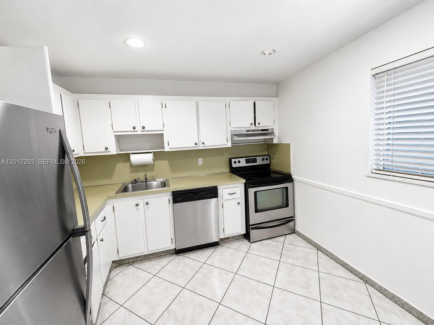 A kitchen features white cabinets, stainless steel appliances, a light countertop, and tiled flooring — 410 SE 2nd St # 415, Hallandale Beach FL 33009, HALLANDALE BEACH, FL