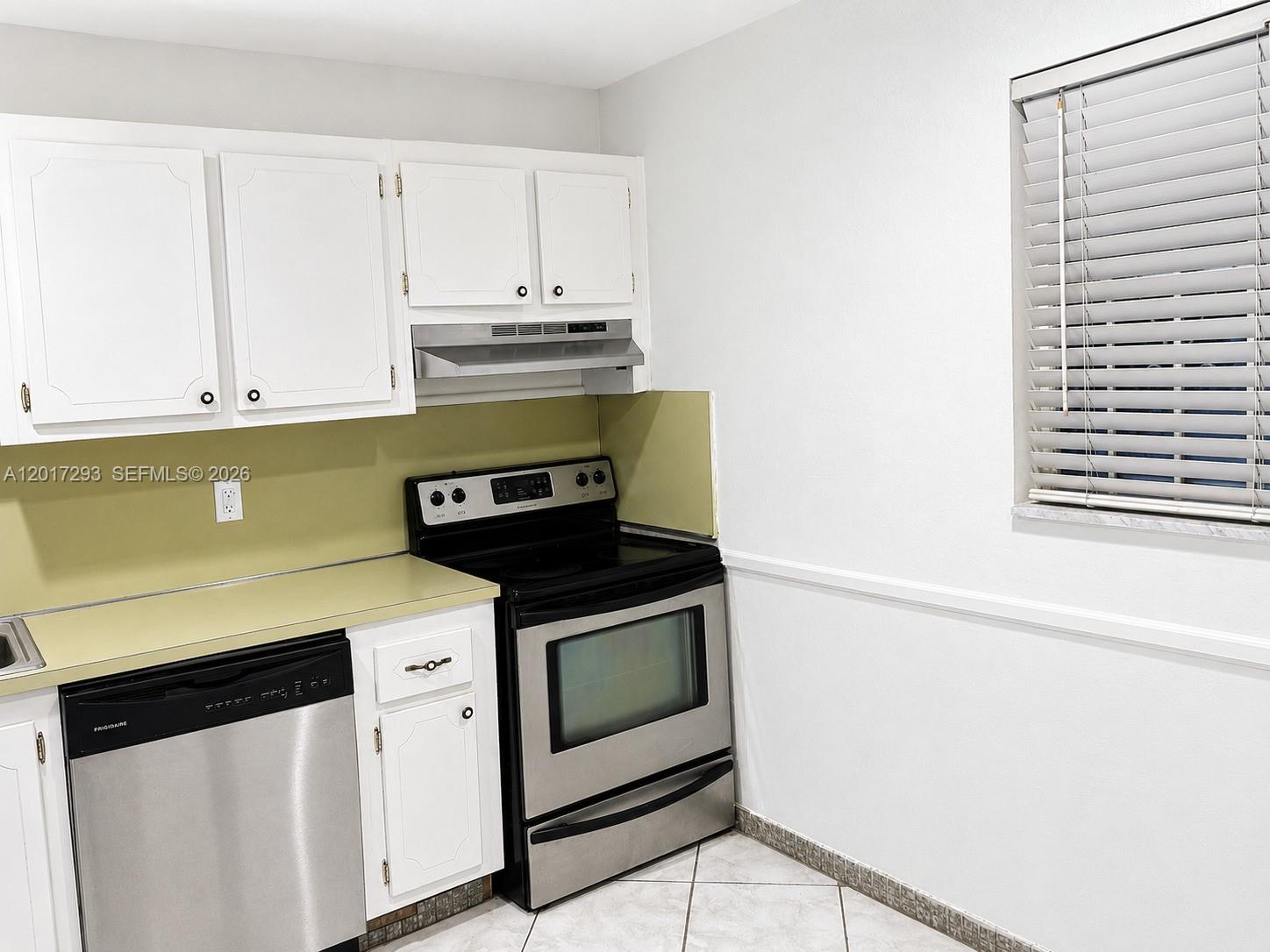 A kitchen features white cabinets, stainless steel appliances, a light green backsplash, and tile flooring — 410 SE 2nd St # 415, Hallandale Beach FL 33009, HALLANDALE BEACH, FL