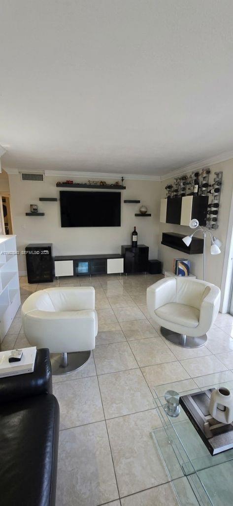A living room features white swivel chairs, a wall-mounted television, and light-colored tile flooring — 5055 NW 7th St # 206, Miami FL 33126, MIAMI, FL