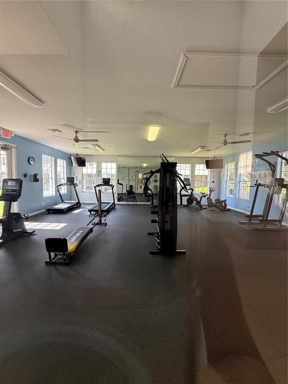 A gym room features rubber flooring, multiple exercise machines, and large windows with natural light — 6214 STEVENSON DRIVE UNIT 305, ORLANDO, FL