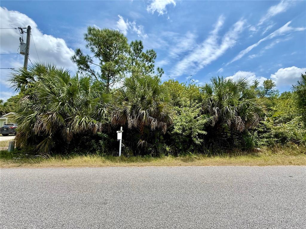 A vacant, wooded lot with palm trees and a real estate sign along a road — ORCHARD CIRCLE, NORTH PORT, FL