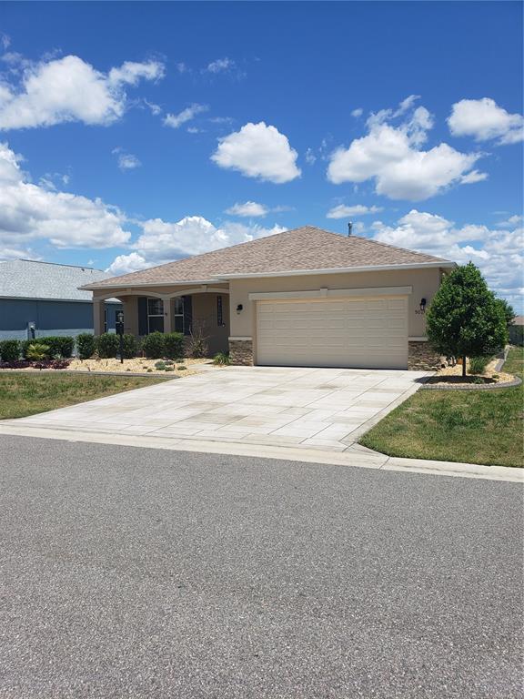 A single-story house with a beige stucco exterior, a paved driveway, and a two-car garage — 9013 SW 79TH LANE, OCALA, FL