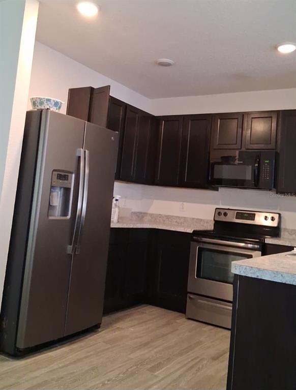 A kitchen features dark wood cabinets, stainless steel appliances, and light-colored countertops — 6656 SEAWAY DRIVE, BROOKSVILLE, FL