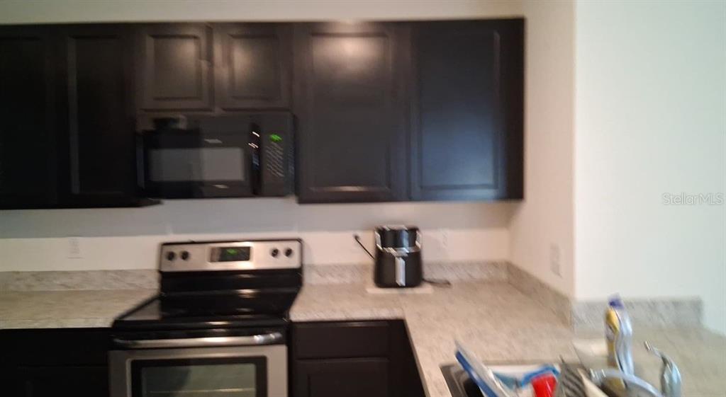 A kitchen features dark wood cabinets, stainless steel appliances, and light-colored granite countertops — 6656 SEAWAY DRIVE, BROOKSVILLE, FL