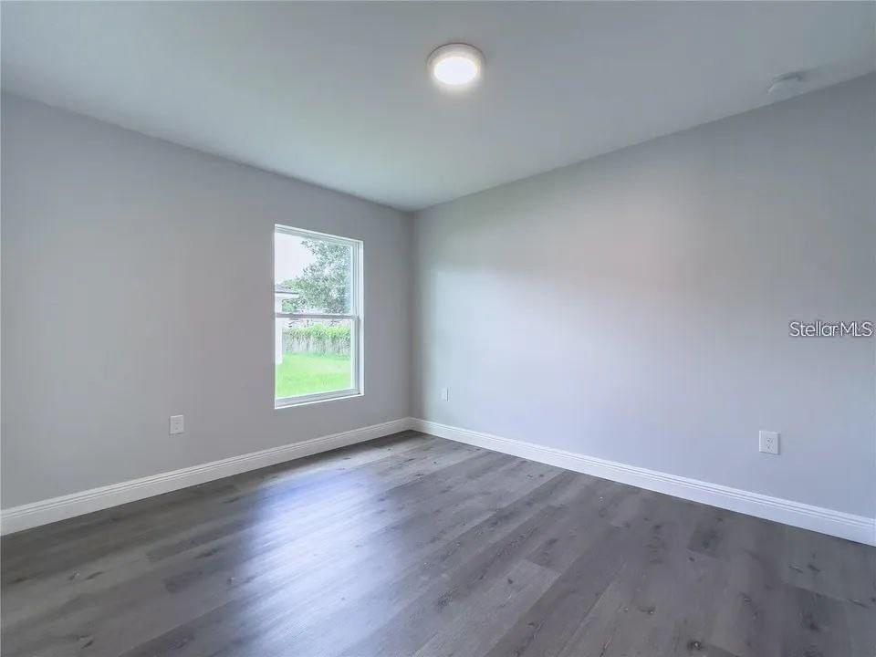 An empty bedroom features light gray walls, wood-look flooring, and a single window — 6688 CHERRY ROAD, OCALA, FL