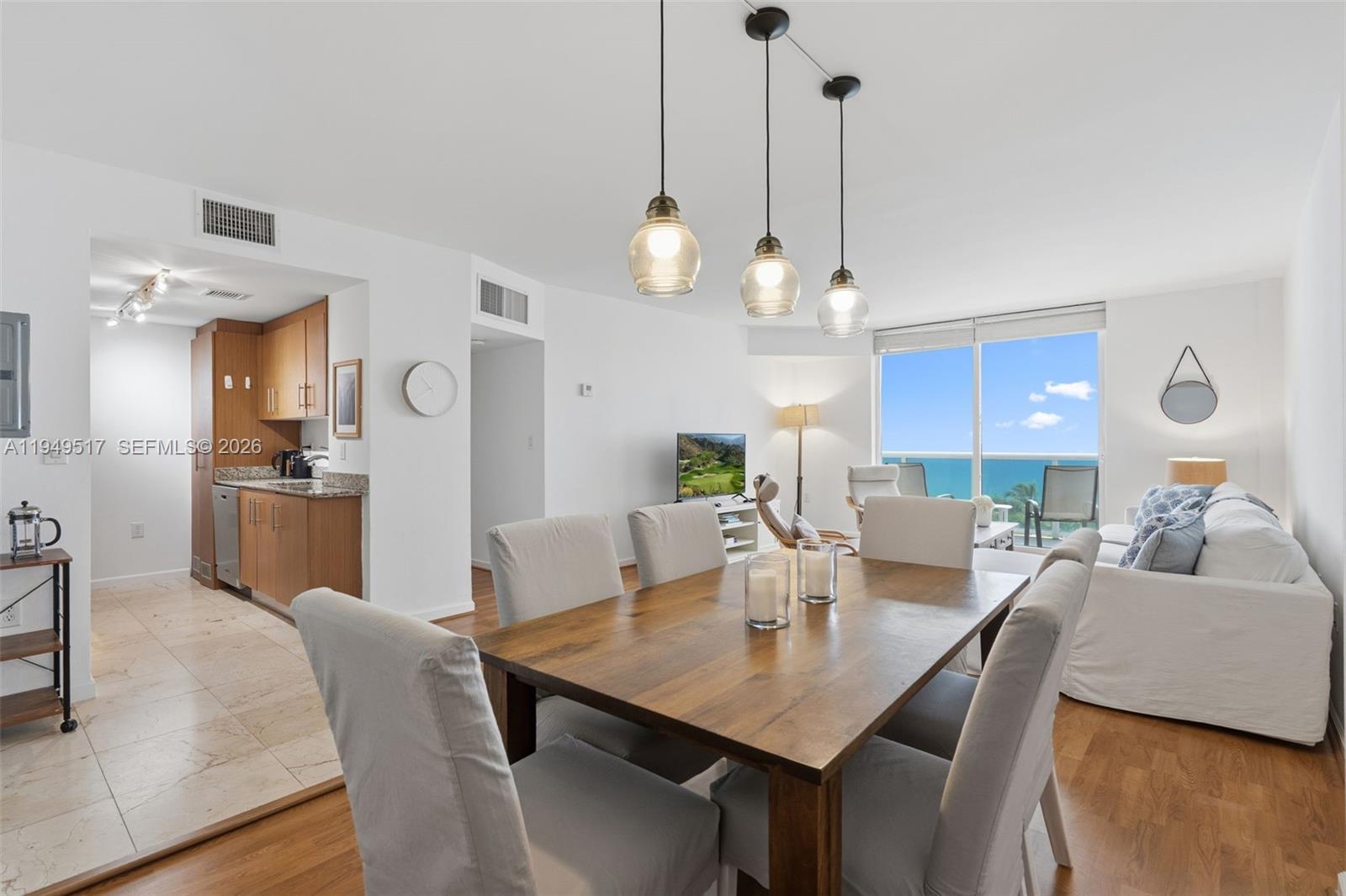 A dining area with a wooden table and pendant lights opens to a living room — 10275 Collins Ave # 718, Bal Harbour FL 33154, BAL HARBOUR, FL