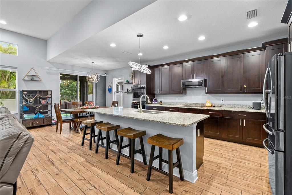 A kitchen with dark wood cabinets, granite countertops, a central island, and wood-look flooring — 7430 71ST AVENUE N, PINELLAS PARK, FL