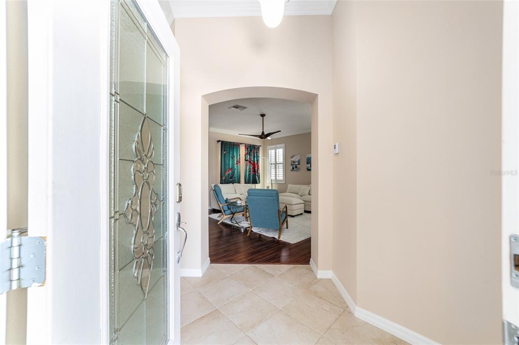 An entryway with tile flooring leads through an arched doorway into a living room — 562 ALLENWOOD LOOP, THE VILLAGES, FL