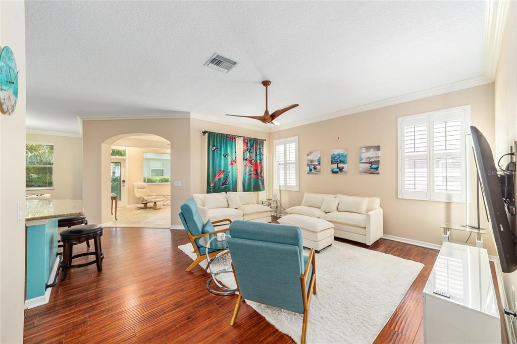 A living room features white sofas, blue armchairs, a white rug, and hardwood floors — 562 ALLENWOOD LOOP, THE VILLAGES, FL