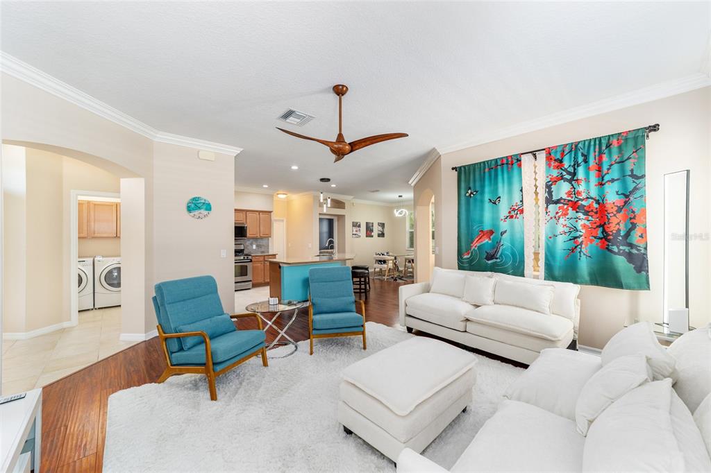 A living room features a white sofa, two blue armchairs, and patterned window curtains — 562 ALLENWOOD LOOP, THE VILLAGES, FL