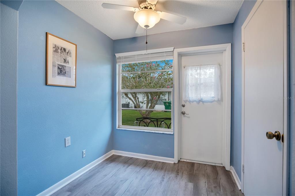 A small room with blue walls, wood-look flooring, a ceiling fan, and a glass-paneled door — 239 N HILL AVENUE UNIT 110, DELAND, FL