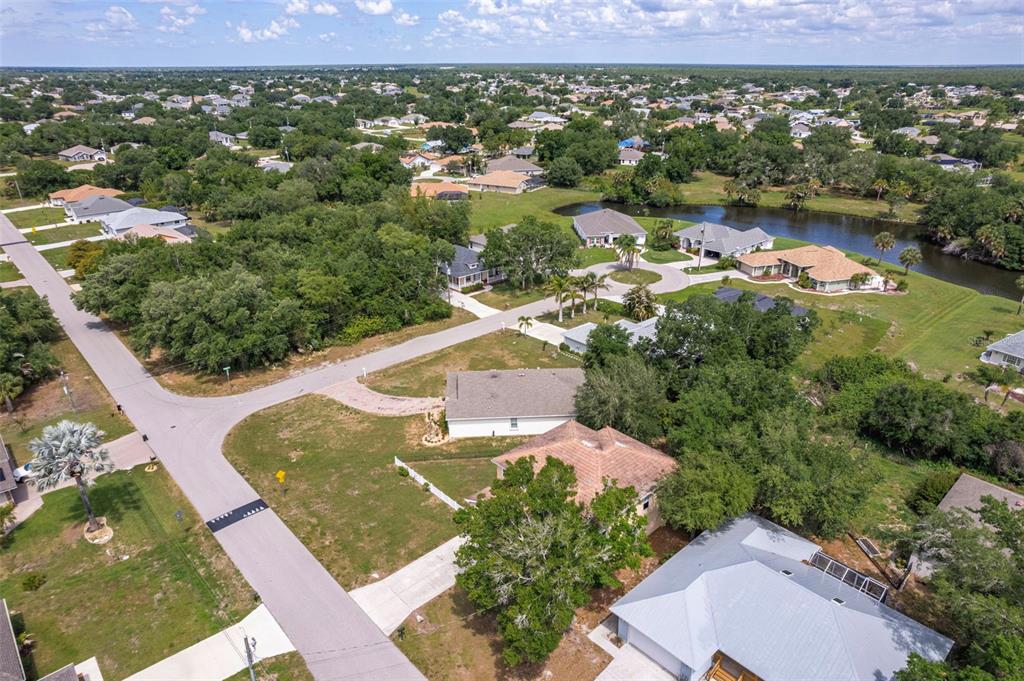 An aerial view shows suburban houses, a winding road, and a pond surrounded by trees — 545 ENCARNACION STREET, PUNTA GORDA, FL