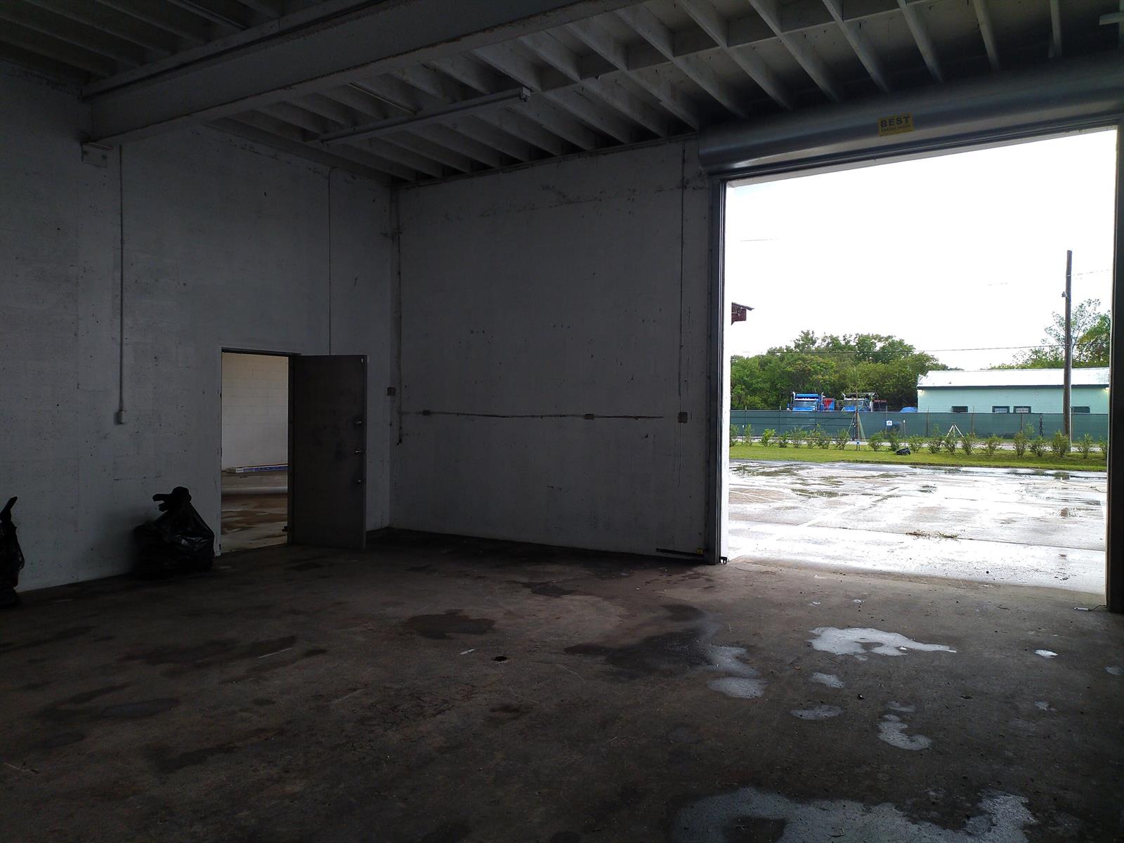 An empty warehouse space with a concrete floor, a side door, and a large open bay — 3625 Metzger Road, Fort Pierce FL 34947, FORT PIERCE, FL