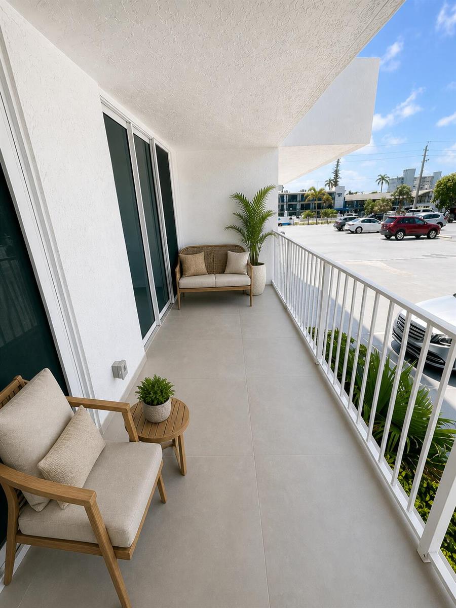 A balcony with light tile flooring, outdoor seating, and a white railing overlooking a parking lot — 800 SE 20th Avenue # 105, Deerfield Beach FL 33441, DEERFIELD BEACH, FL