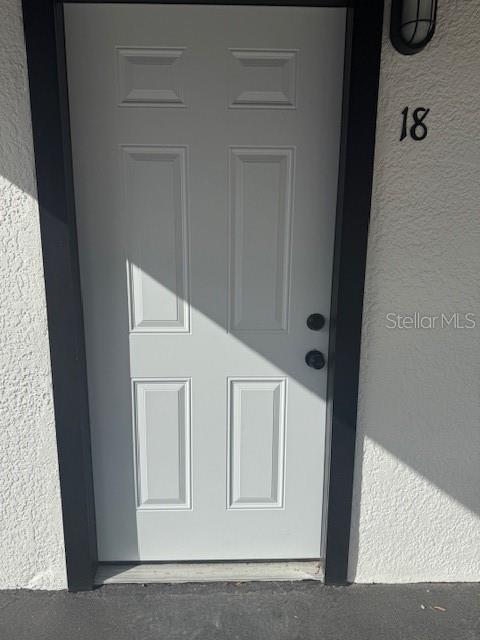 A white six-panel exterior door with black trim and the number 18 above it — 4605 N HUBERT AVENUE UNIT 18, TAMPA, FL