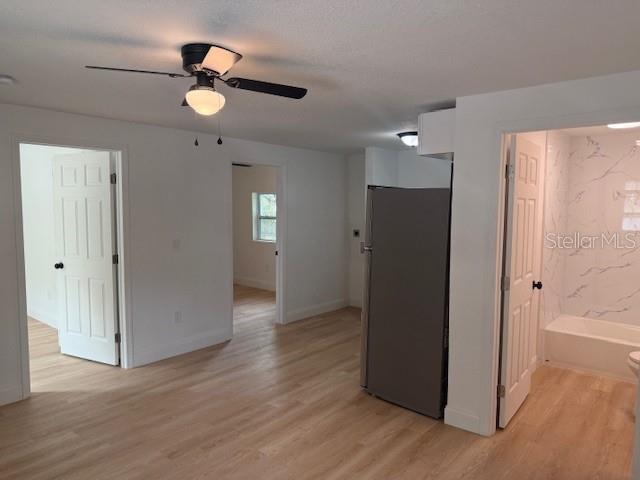 An interior view shows a room with light wood flooring, a ceiling fan, and doorways — 4605 N HUBERT AVENUE UNIT 18, TAMPA, FL