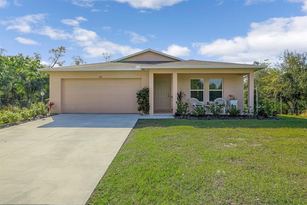 A single-story house with a beige exterior, a two-car garage, and a covered front porch — 1091 CAZENOVIA STREET, PORT CHARLOTTE, FL