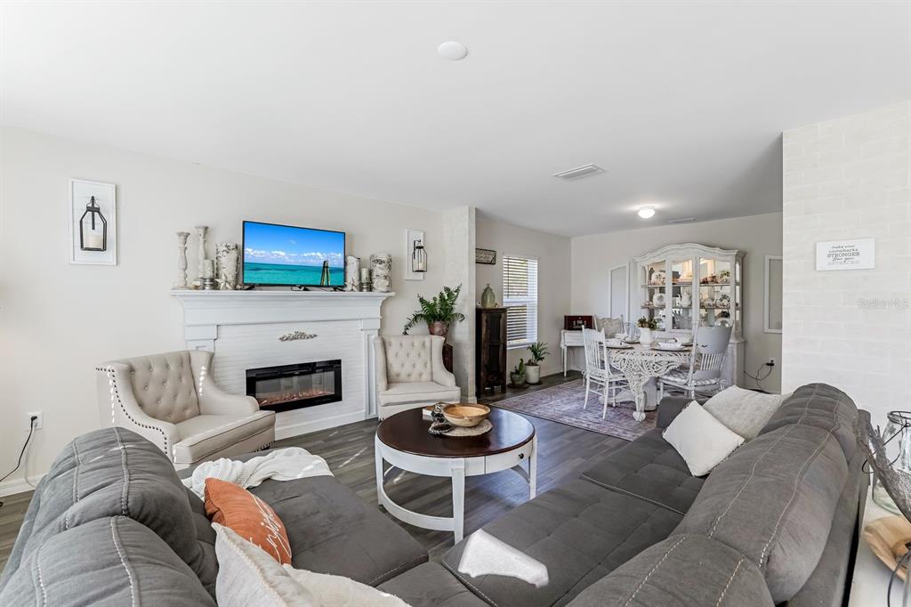 A living room with a fireplace, television, gray sectional sofa, and an adjacent dining area — 1091 CAZENOVIA STREET, PORT CHARLOTTE, FL