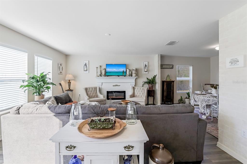 A living room features a gray sectional sofa, a fireplace with a television, and dining area — 1091 CAZENOVIA STREET, PORT CHARLOTTE, FL
