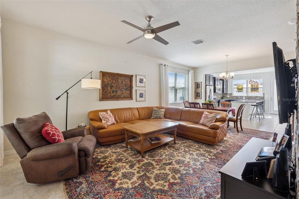 A kitchen features dark wood cabinets, granite countertops, a central island, and stained glass window accents — 7279 DUXBURY LANE, WINTER GARDEN, FL