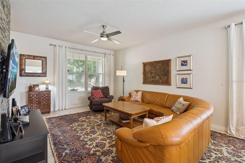 A living room features a brown leather sectional, a recliner, and a patterned area rug — 7279 DUXBURY LANE, WINTER GARDEN, FL