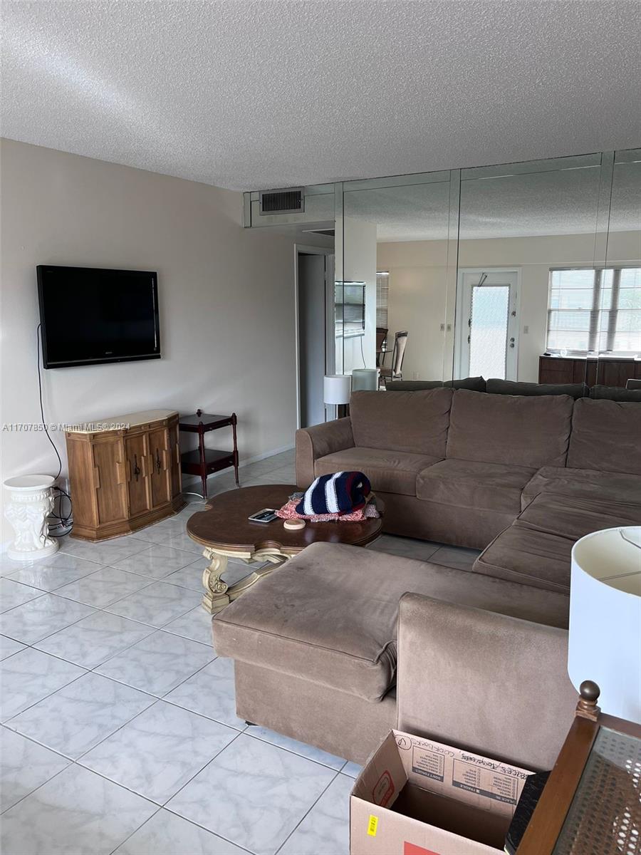 A living room features a brown sectional sofa, a television, and a mirrored wall — 324 Fanshaw H # H, Boca Raton FL 33434, BOCA RATON, FL