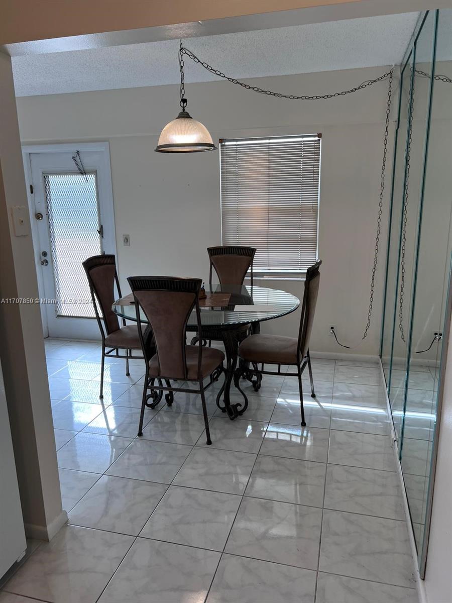 A dining area features a glass-topped table, four chairs, tile flooring, and a pendant light — 324 Fanshaw H # H, Boca Raton FL 33434, BOCA RATON, FL