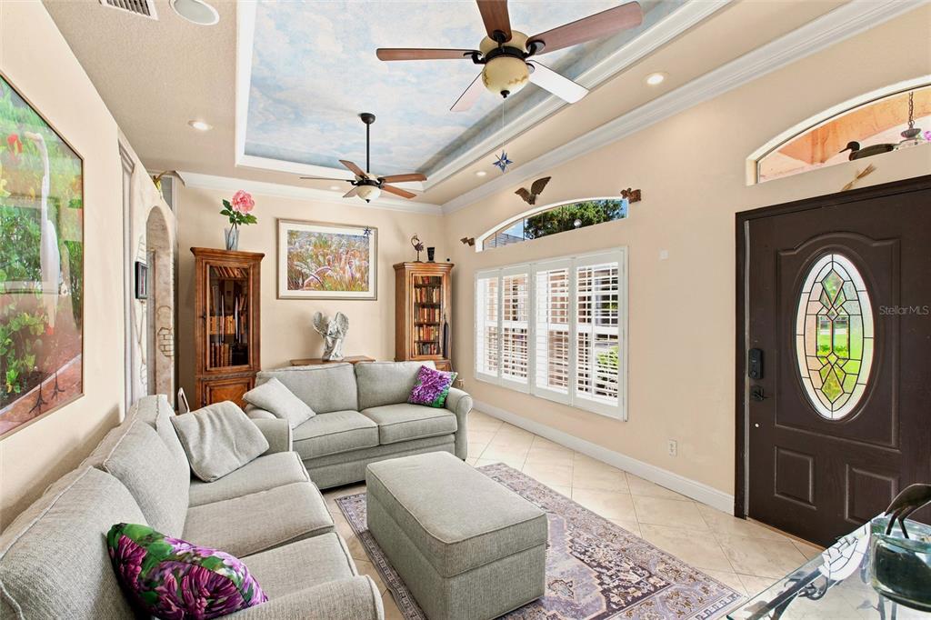 A living room features a tray ceiling with a sky mural, two ceiling fans, and tile flooring — 652 N ELM STREET, ENGLEWOOD, FL
