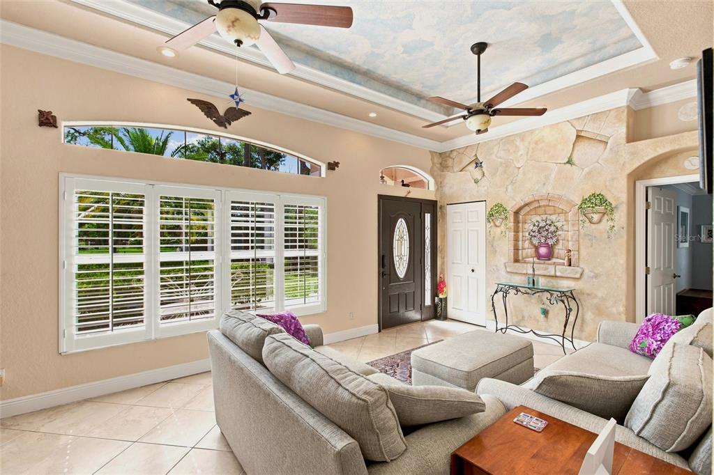 A living room features a cloud-painted tray ceiling, stone accent wall, and tile flooring — 652 N ELM STREET, ENGLEWOOD, FL