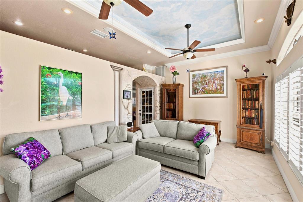 A living room features two gray sofas, a matching ottoman, and a painted sky ceiling — 652 N ELM STREET, ENGLEWOOD, FL