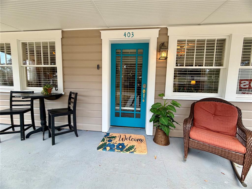 A front porch features a teal door, a bistro set, and a wicker rocking chair — 403 W CHELSEA STREET, TAMPA, FL