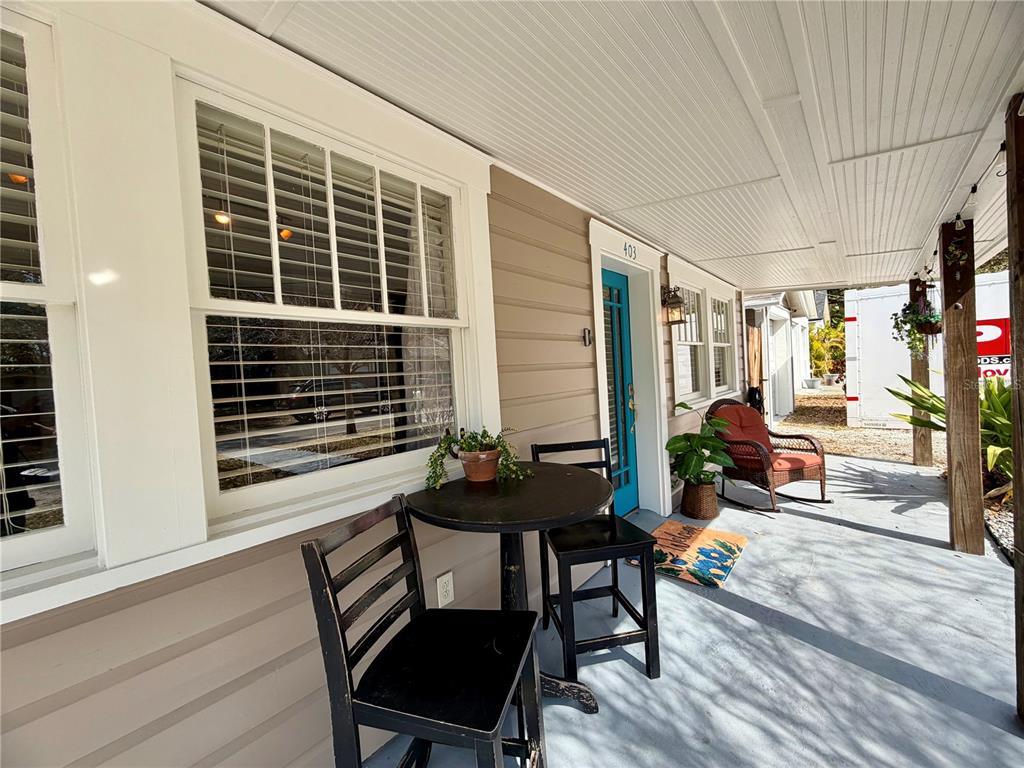 A covered front porch features a small bistro set, a rocking chair, and a blue door — 403 W CHELSEA STREET, TAMPA, FL