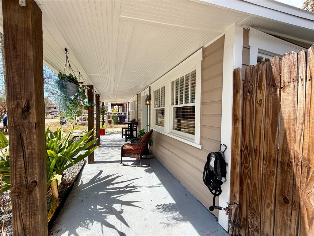A covered porch features a gray concrete floor, wooden posts, and a wooden privacy fence — 403 W CHELSEA STREET, TAMPA, FL