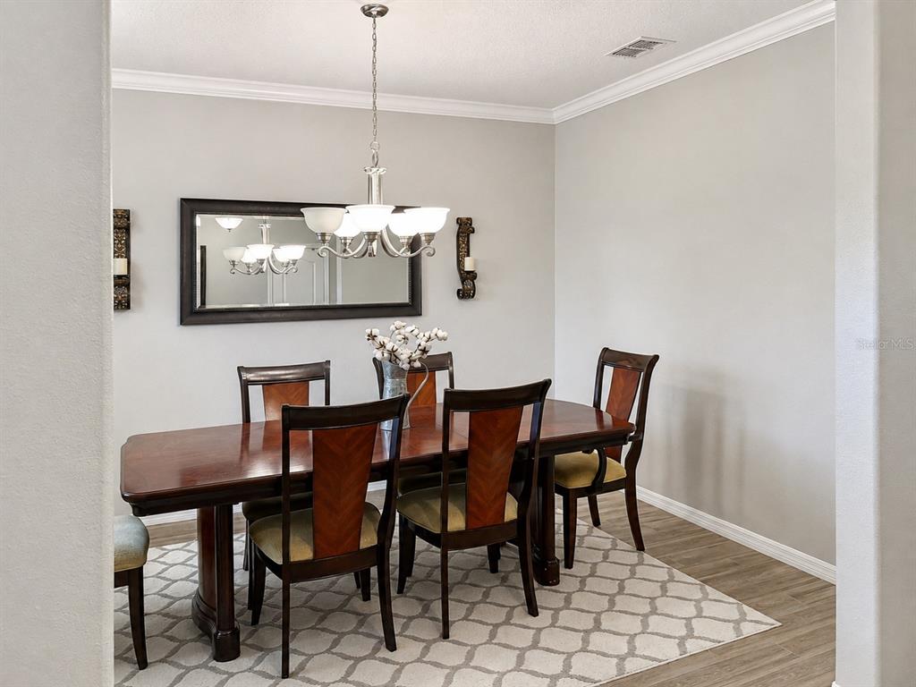 A dining room features a wooden table, six chairs, a chandelier, and a wall mirror — 3244 BERWICK LANE, LAKELAND, FL