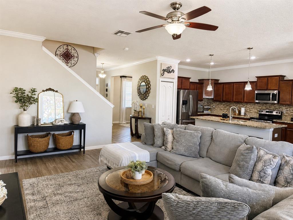 An open-concept living room and kitchen feature a gray sectional, wood floors, and dark cabinetry — 3244 BERWICK LANE, LAKELAND, FL